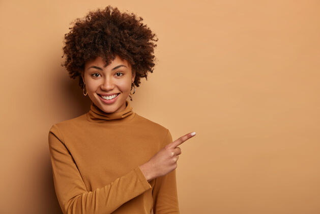 毛衣一位留着非洲式发型 面容友好的女士 在复印区右指右指 展示新产品 做促销广告高兴女性地点