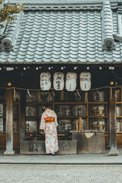 人穿着橘色和白色和服的女人站在房子附近探索神社京都