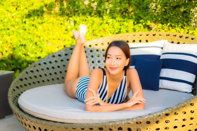 度假村肖像美丽的年轻女子放松微笑休闲度假酒店游泳池周围成人阳光身体