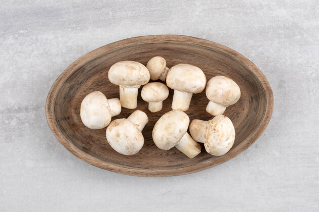 生的一块用新鲜白蘑菇做成的木板放在石头表面新鲜有机美味