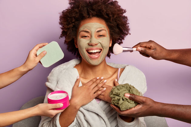 美容快乐的美国黑人女人真诚地笑着 敷上剥皮面膜 同时得到不同的美容治疗家庭手面膜