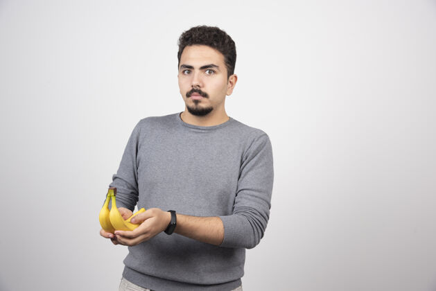 人黑发男子拿着香蕉在灰色的指向男人水果