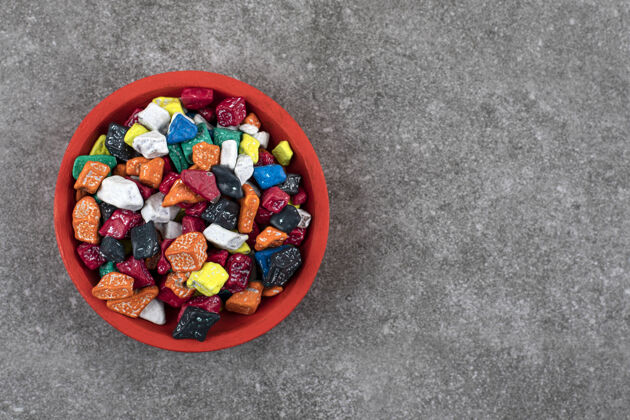 岩石红碗五颜六色的石头糖果放在石头上各色糖果甜点