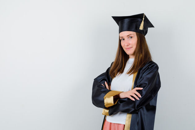 女孩毕业的女人 穿着休闲服 穿着制服 双臂交叉站着 看起来很自信正面图大学毕业典礼Cap