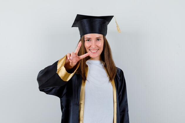 年轻女学生穿着毕业礼服 露出v字标志 看上去很开朗 正面照学位VSu签欢呼