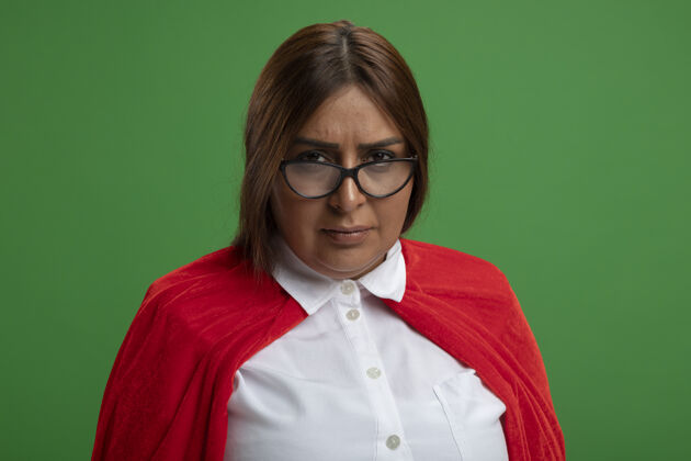 相机严格的中年女超人戴着眼镜看着隔离在绿色背景上的相机严格中年穿