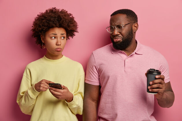不满意不幸的非洲女人在智能手机里用悲伤的表情展示了一些东西男性沮丧女性