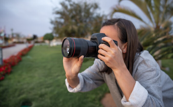 光学女孩在户外用专业单反相机拍了一张自然特写的照片女人肖像爱好