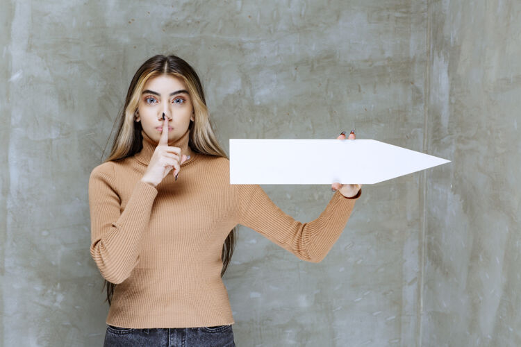 标志美丽的女人拿着箭在石头上做无声的手势年轻漂亮年轻