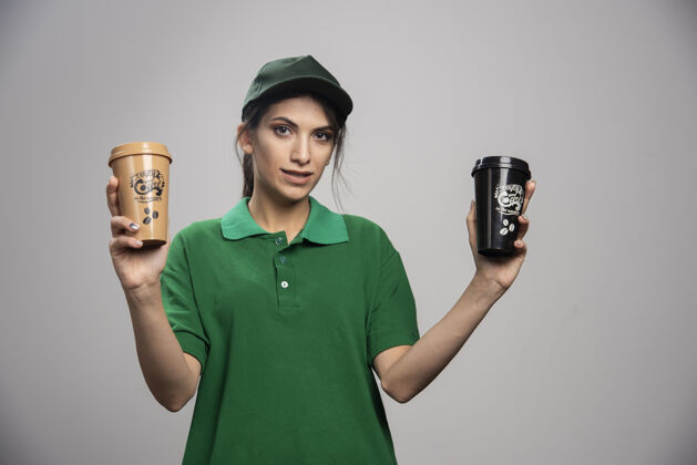 工人穿着绿色制服的女送货员摆出美味咖啡的姿势送货员工承运人