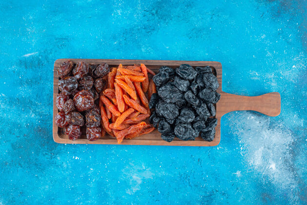 天然把干李子和杏子放在蓝色的木板上风味营养水果