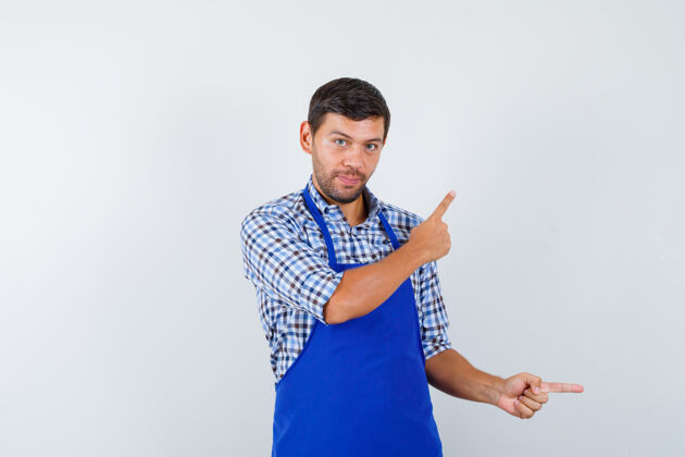 烹饪穿着蓝色围裙和衬衫的年轻男厨师男士衬衫制服