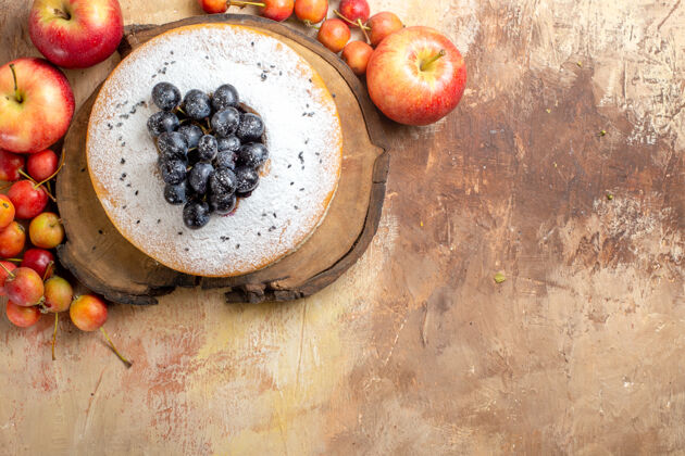 灌木浆果俯视图在木板上放着葡萄的蛋糕苹果和浆果木材蛋糕葡萄