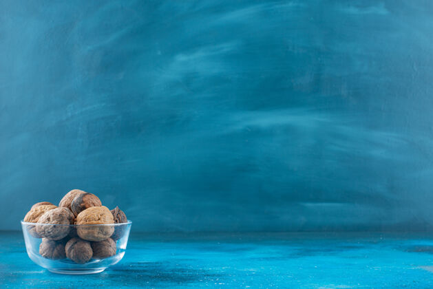 美味核桃壳放在一个蓝色的玻璃碗里健康玻璃碗坚果