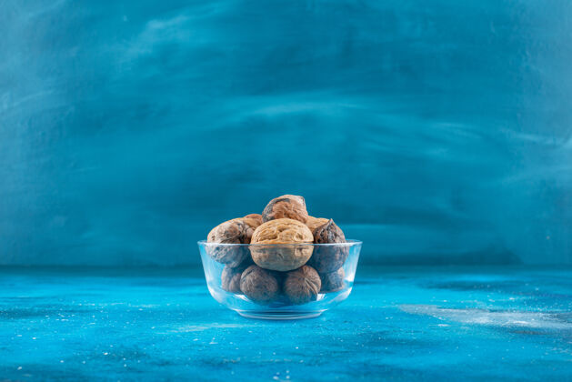 玻璃碗核桃壳放在一个蓝色的玻璃碗里风味健康自然