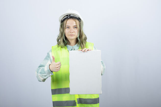 建筑美丽的女工程师举着空帆布竖起大拇指的照片高质量的照片工作人制服