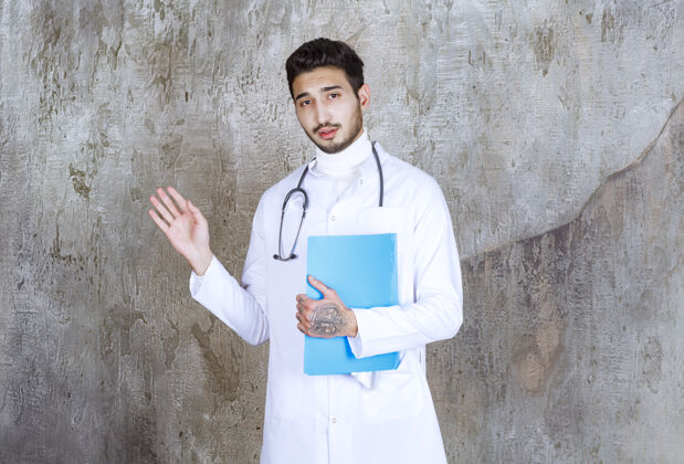 从业者男医生拿着听诊器拿着一个蓝色文件夹和周围的人互动医生制服姿势