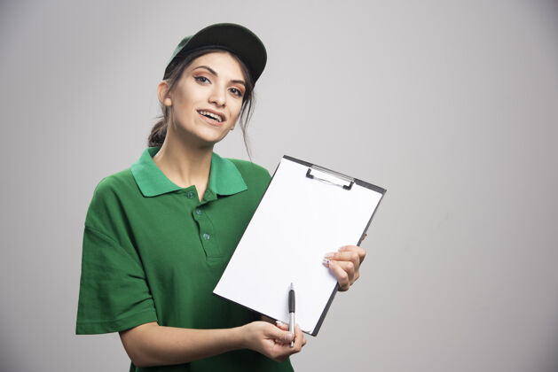 女人穿着绿色制服的女送货员在哪里签字职业剪贴板女孩