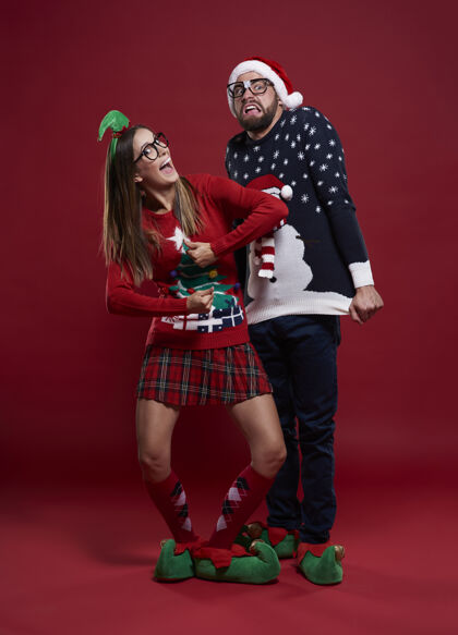 圣诞帽穿着奇怪圣诞服装的年轻夫妇圣诞毛衣调情圣诞节