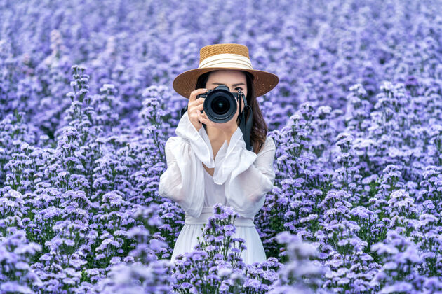 草地游客在玛格丽特花坛用数码相机拍照快乐泰国相机