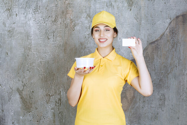 制服身穿黄色制服的女快递员手持外卖杯 出示名片名片年轻人员工