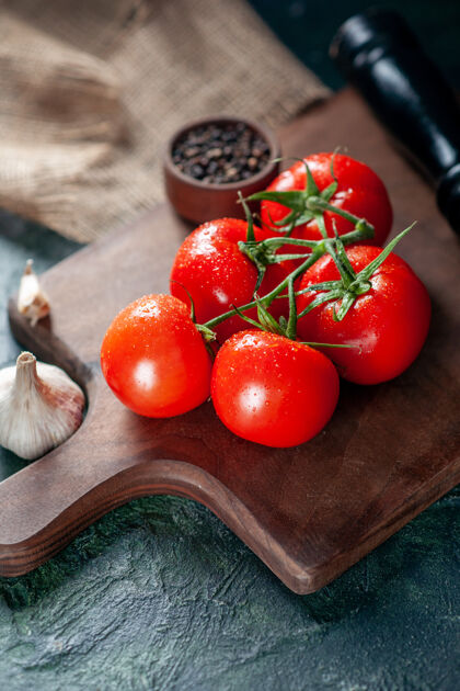 西红柿前视图新鲜的红色西红柿和大蒜在黑暗的背景饮食沙拉大蒜
