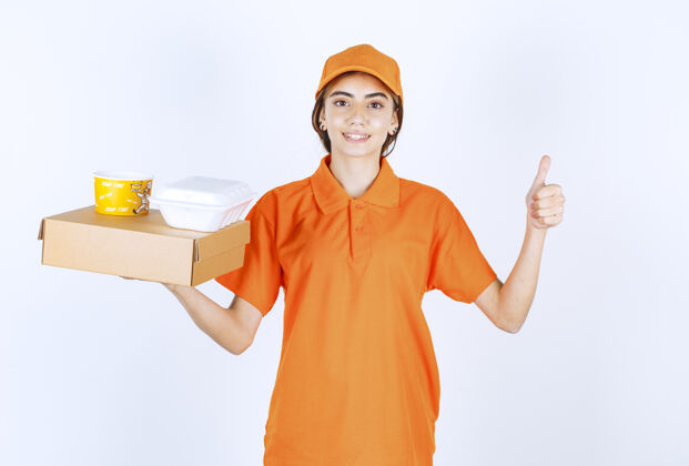 送货身着橙色制服的女快递员手里拿着黄白相间的外卖箱姿势精力成功