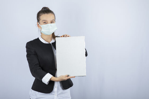 感染戴着面具的年轻女子的照片 白色墙壁上覆盖着空白画布高质量照片疾病医学流行病