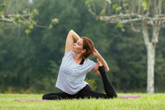 瑜伽年轻漂亮的女人在绿色公园做瑜伽练习健康的生活方式和健身理念放松姿势女孩