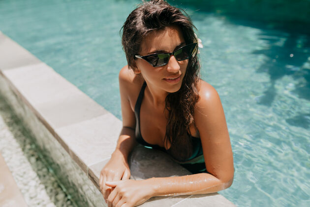 幸福在阳光明媚的温暖日子里 一头乌黑长发的快乐迷人的欧洲女士在度假胜地休息 在游泳池里游泳天堂孤独司机