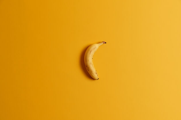 香蕉一根成熟的香蕉在黄色背景上的俯视图美味的热带水果为您的美味早餐或零食全香蕉即食有益的营养产品 富含维生素小吃生的营养素