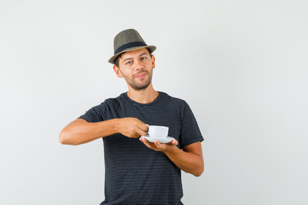 男人年轻的男子拿着一杯咖啡 戴着t恤帽子 看上去很高兴表情T恤专业