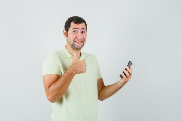 现代一个年轻人拿着计算器 穿着t恤衫竖起大拇指 看上去很高兴胡须向上男性