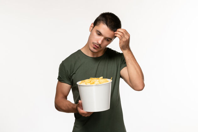 杯子正面图身穿绿色t恤的年轻男性 带土豆cips思考白墙电影人男性孤独电影电影院年轻男性土豆电影