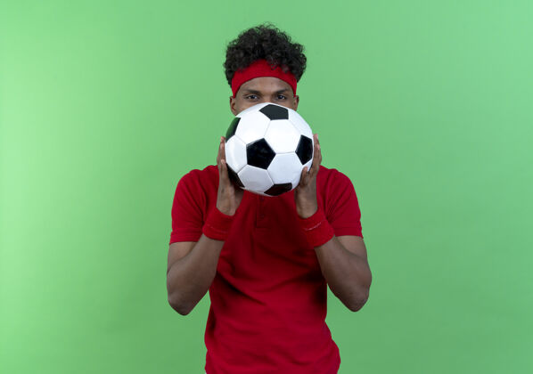 相机看着镜头 年轻的美国黑人运动男子戴着头带和腕带 脸上贴着球 背景是绿色的球非裔美国人封面