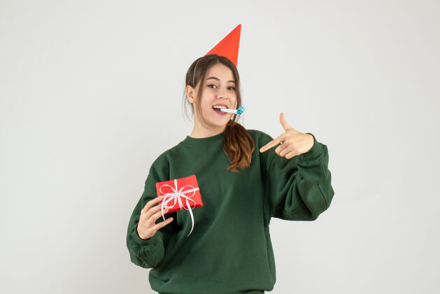 聚会前视图幸福的女孩与党的帽子指着她的圣诞礼物帽子微笑幸福的女孩