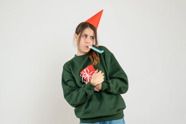 成人前视图激动的女孩与党的帽子隐藏她的圣诞礼物使用noisemaker空间人职业
