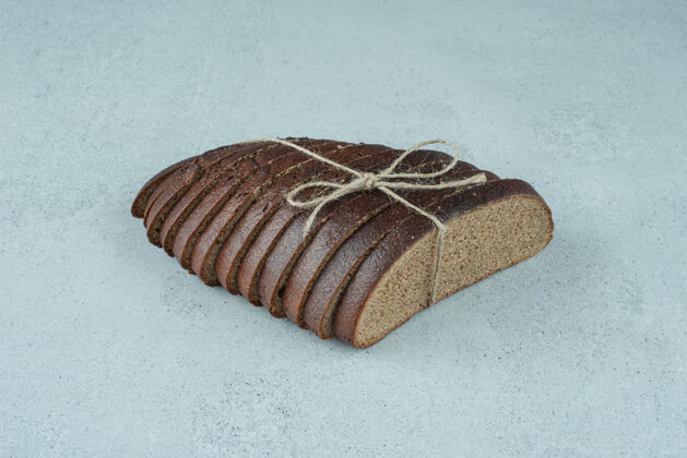 饮食用绳子绑在石头表面的黑面包片有机食品切片