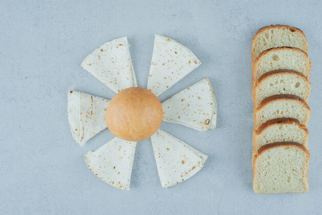 顶视图在石头表面上放面包 香肠和面包片新鲜面包拉瓦什