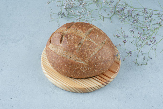面包黑麦面包卷放在木板上 上面有植物棕色整个面包卷