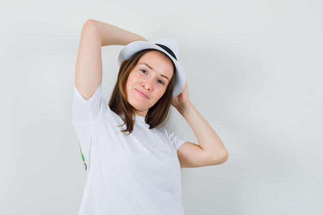 手戴着白色t恤帽子的年轻女士手举在头上 看起来很自信积极帽子女性
