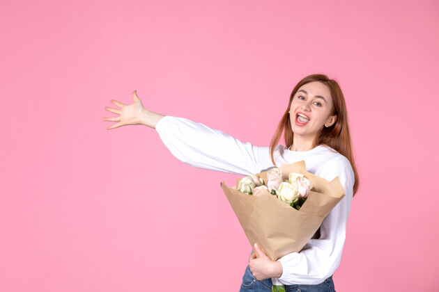 人正面图：带花朵的年轻女性 作为女性节礼物 粉色背景 横向女性三月女性性感约会平等爱情花束年轻的女性玫瑰