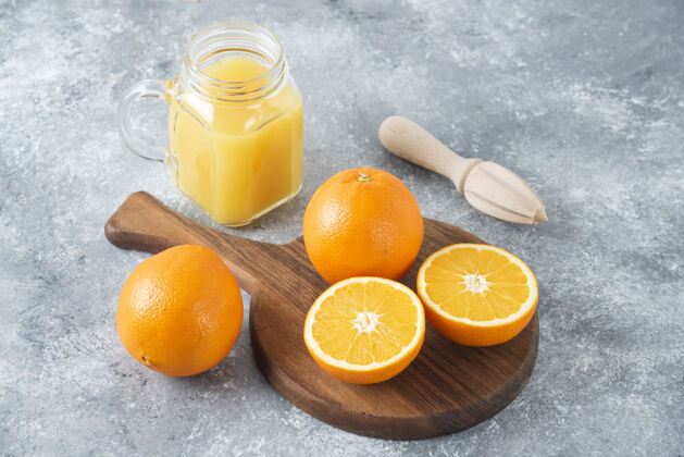 异国情调石桌上放着一杯果汁和新鲜的橙子多汁成熟新鲜