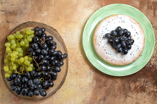 木材顶视图葡萄一串串的黑葡萄和绿葡萄放在木板上 蛋糕上放着葡萄可食用的水果板饮食