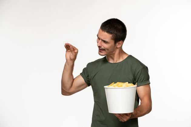 肖像正面图身穿绿色t恤的年轻男子拿着篮子 白色墙上挂着cips电影《男性孤独》电影院侍者杯子电影