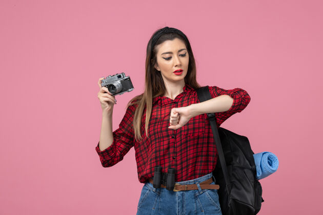 微笑正面图：穿着红色衬衫的年轻女性 在粉色地板上用相机拍摄模特照片人成人年轻女性
