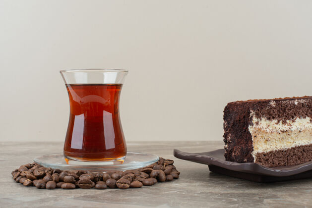 可可在大理石桌上放一片巧克力蛋糕 咖啡豆和一杯茶面包房甜点蛋糕
