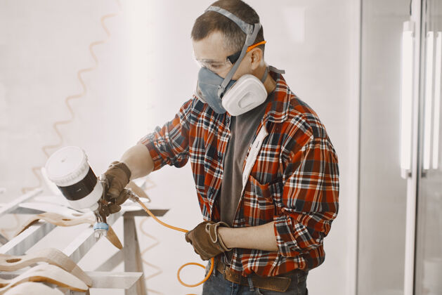 人一个工厂里的油漆用喷枪画木头翻新职业工艺
