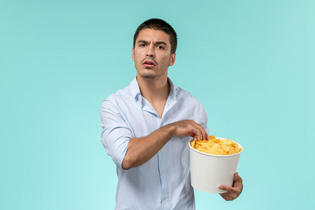 实验室外套正面图年轻人拿着篮子和土豆在浅蓝的墙上吃着看电影孤独的遥远的电影院成人男人杯子