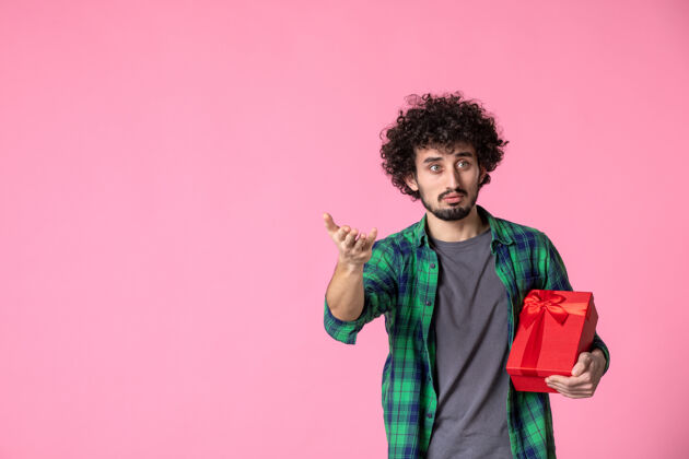 红色包装浅粉色墙上红色包裹的年轻男性正面图人文案礼物